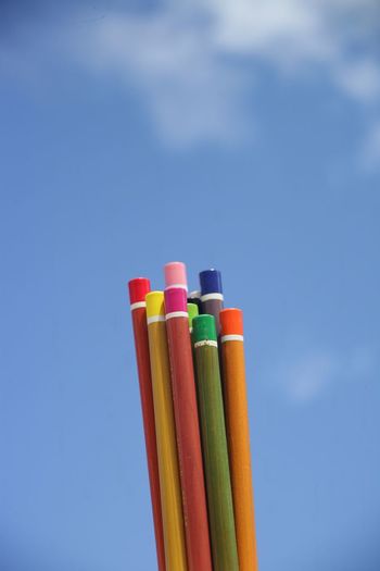 Close-up of colored pencils against blue sky