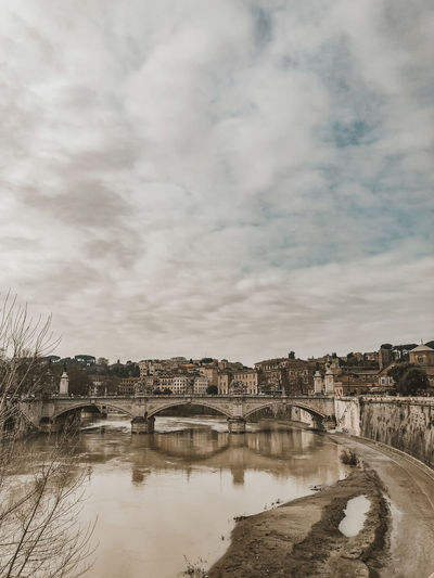 Bridge over river with buildings in background in rome