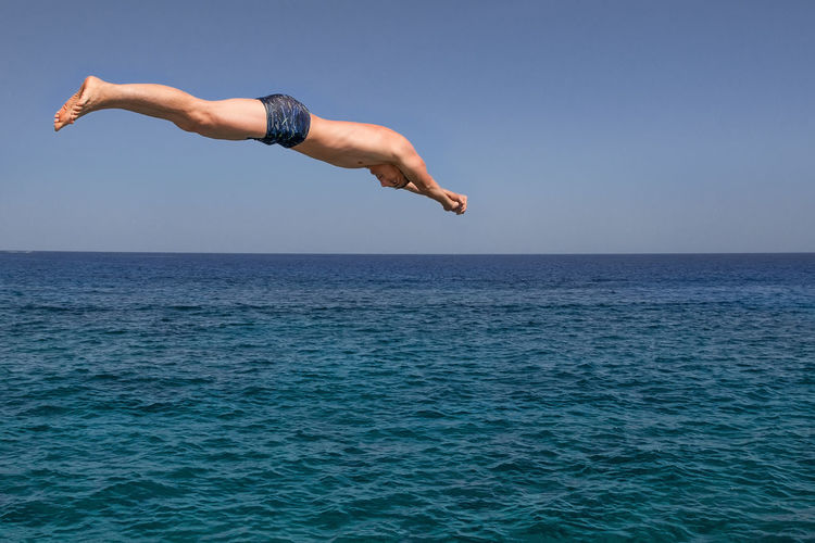 Man jumping in sea against clear sky