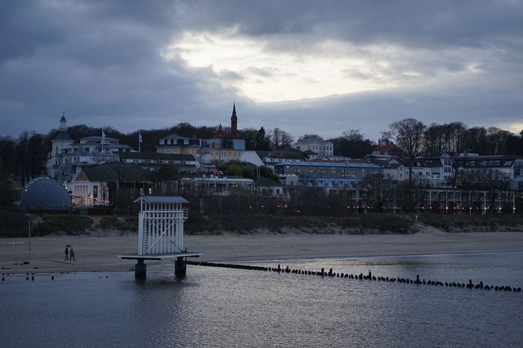 Buildings by river against sky in city during winter