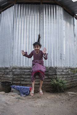 Portrait of girl jumping against corrugated iron