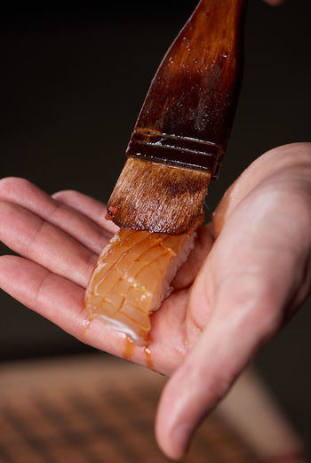Close-up of hand applying sauce of salmon