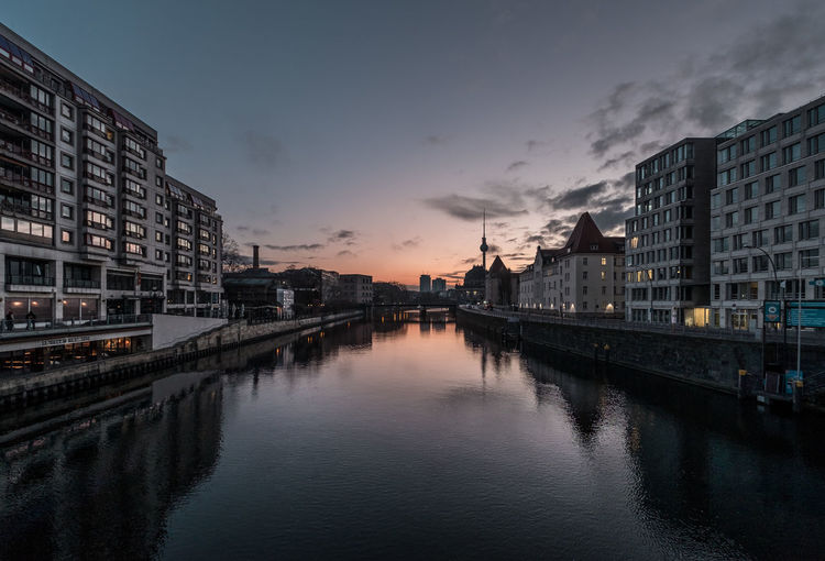 Bridge over river amidst buildings in city against sky