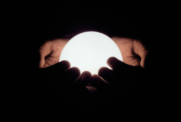 Close-up of hand holding light over black background