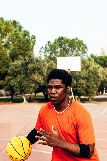 Young man playing with basketball at court