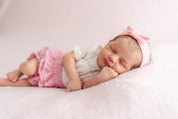 A newborn baby girl with a headband sleeping peacefully. newborn session concept