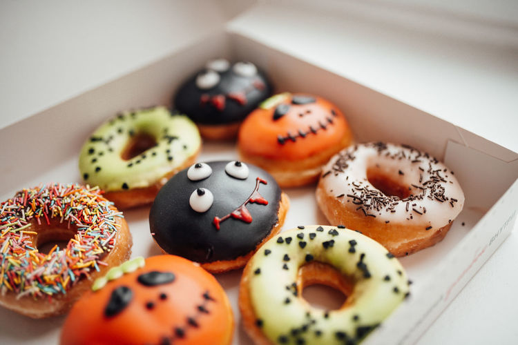Assortment of halloween monsters with funny faces donuts in box at home interior