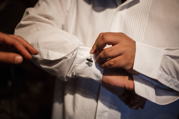 Midsection of groom adjusting cufflinks