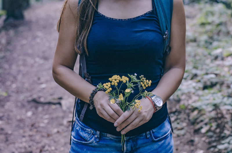 Midsection of woman holding bouquet at field