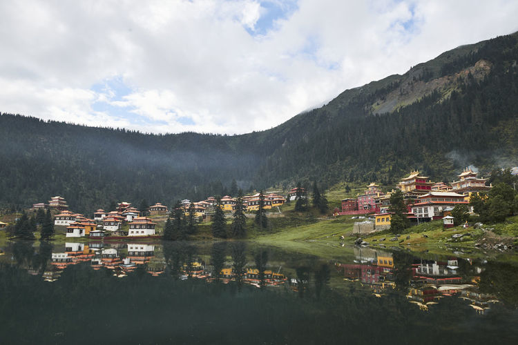 Houses by lake and buildings against sky