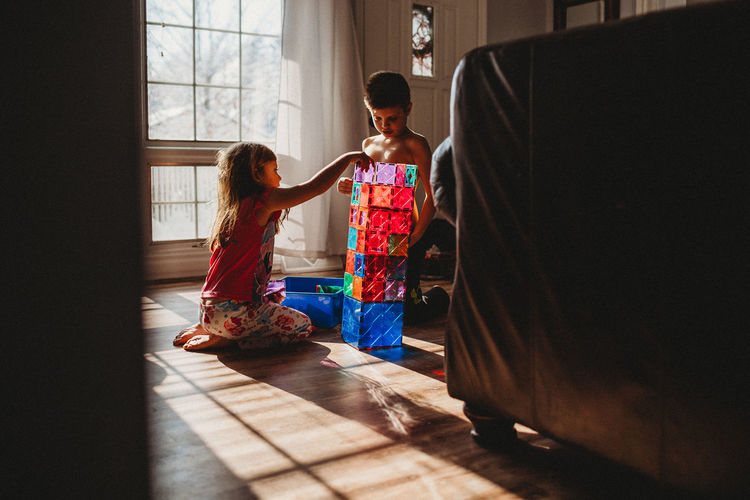Boy and girl stacking toy blocks on floor