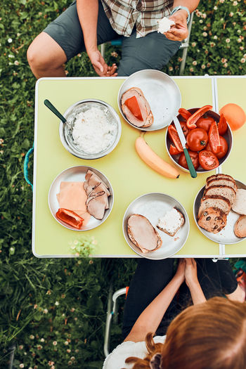 Family having breakfast outdoors on camping during summer vacation. bread, cottage cheese, cold meat