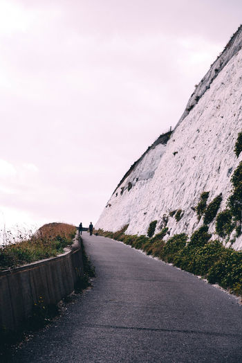 Road by cliff against sky