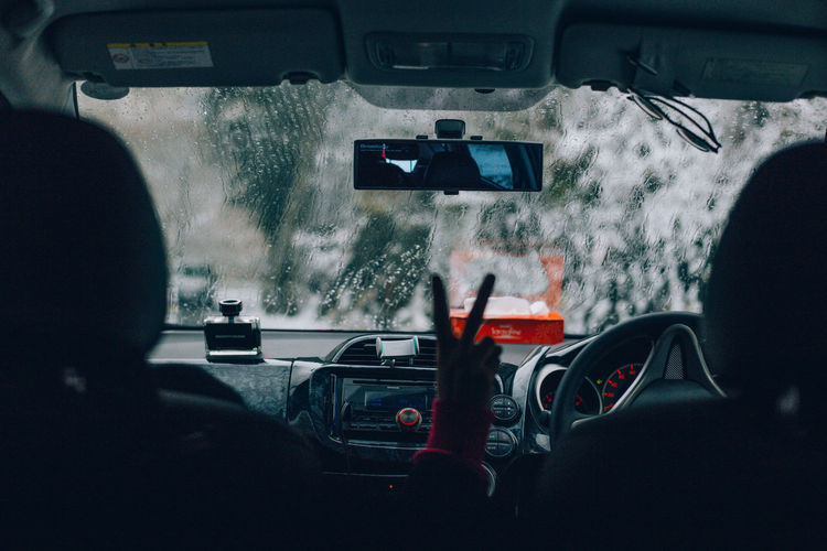 Man gesturing while sitting in car during rainy season