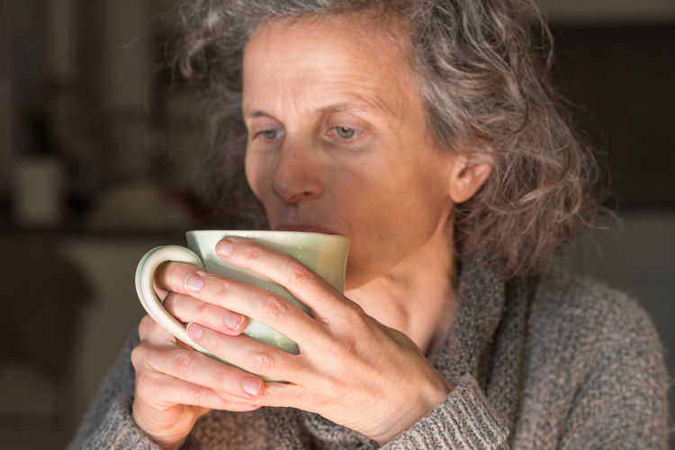 Close-up portrait of woman holding coffee cup