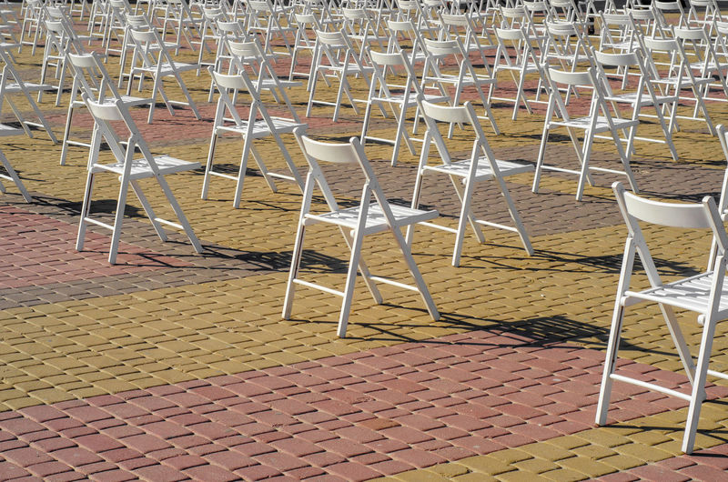 White folding chairs are placed on square on pavement. quarantine, events, a concert on street