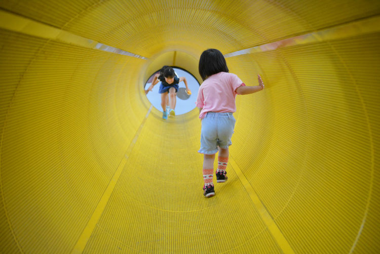 Girls walking in yellow tunnel at playground