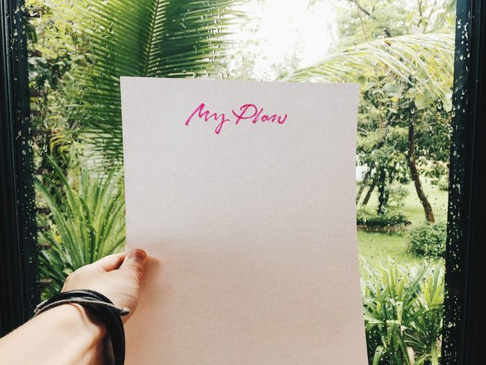 Person holding hand written paper list against window