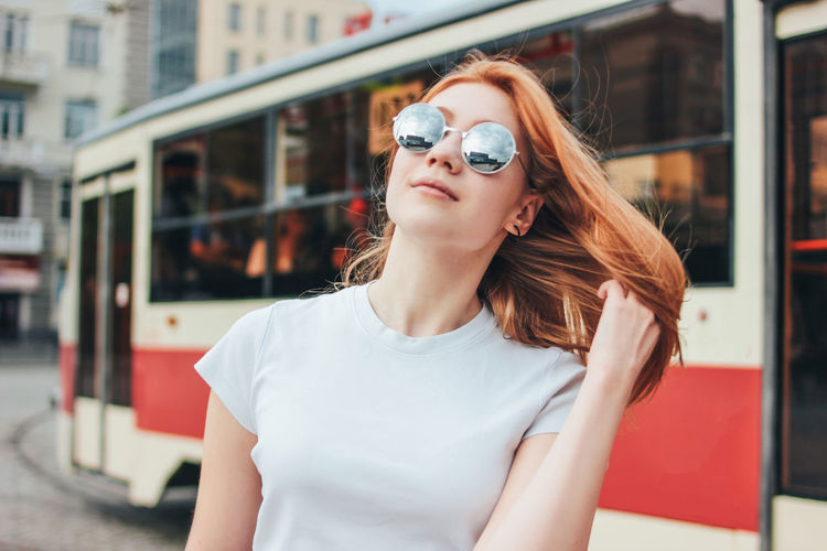 Portrait of beautiful woman wearing sunglasses while standing on city street