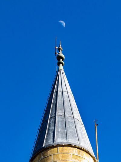 A moon rises midday over the top of the mosque tower, cyprus.