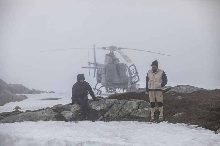 Helicopter pilot and passenger wait for improved weather, stranded.