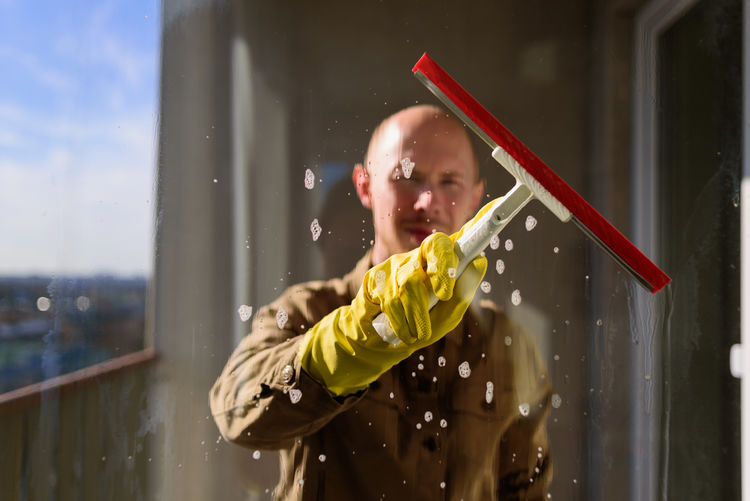 Portrait of man cleaning the glass of office window