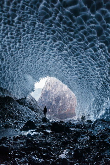 Rear view of silhouette person standing in frozen cave