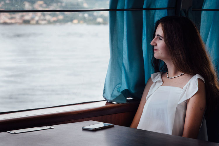 Close-up of young woman looking through window while sitting in boat