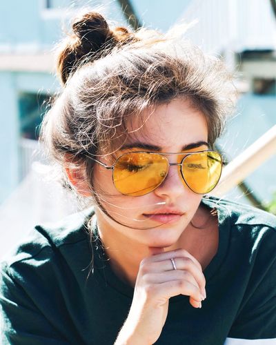 Close-up of young woman wearing yellow sunglasses outdoors