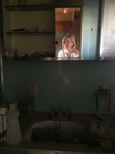 Woman reflecting on mirror in abandoned room