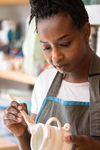 Female ceramic artist glazing a cup