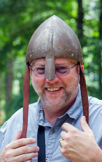 A modern day man poses wearing a medieval helmet called a cervelliere,