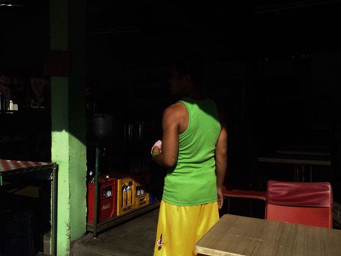 Rear view of man standing in illuminated room