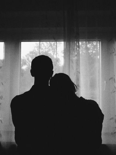 Rear view of silhouette man and woman standing against window