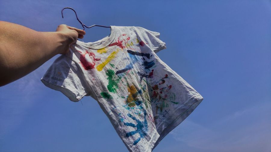 Low angle view of hand holding child's painted t shirt 