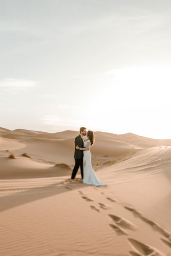 Rear view of couple standing on sand dune