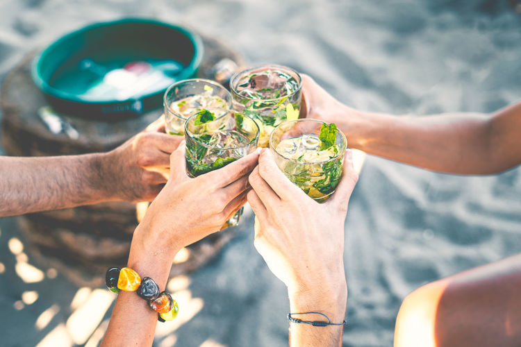 High angle view of group of people toasting holding glass with tropical  cocktails