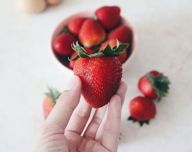 Close-up of cropped hand holding strawberries
