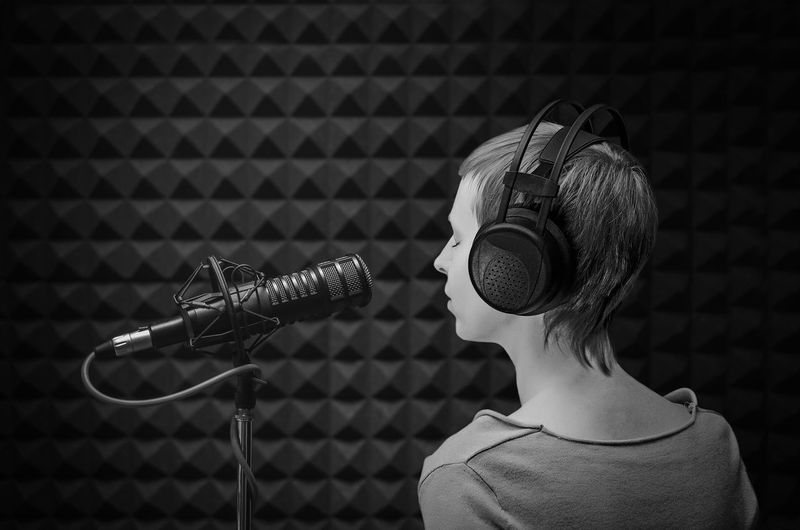 Girl announcer at the microphone in the studio with acoustic panels