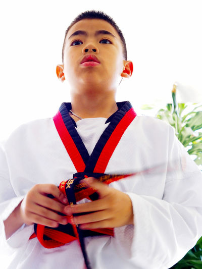 Portrait of boy holding camera over white background