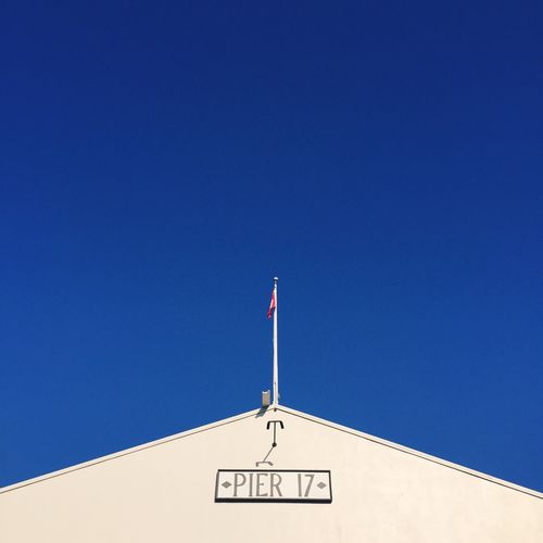 Low angle view of pier 17 text on building against clear blue sky