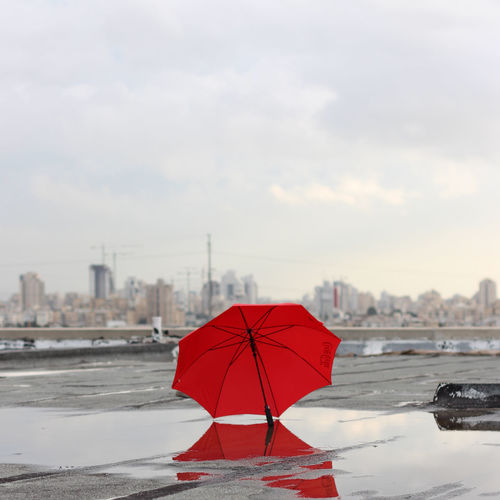 Red umbrella on beach against sky in city