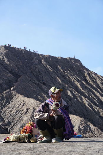 People sitting on rock against mountains