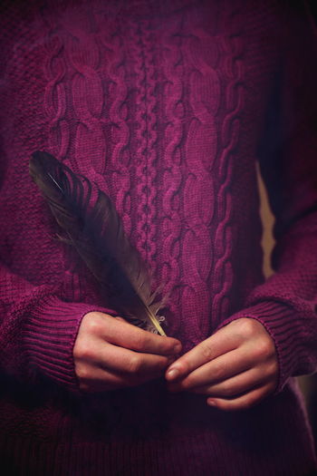 Close-up mid section of a woman holding feather