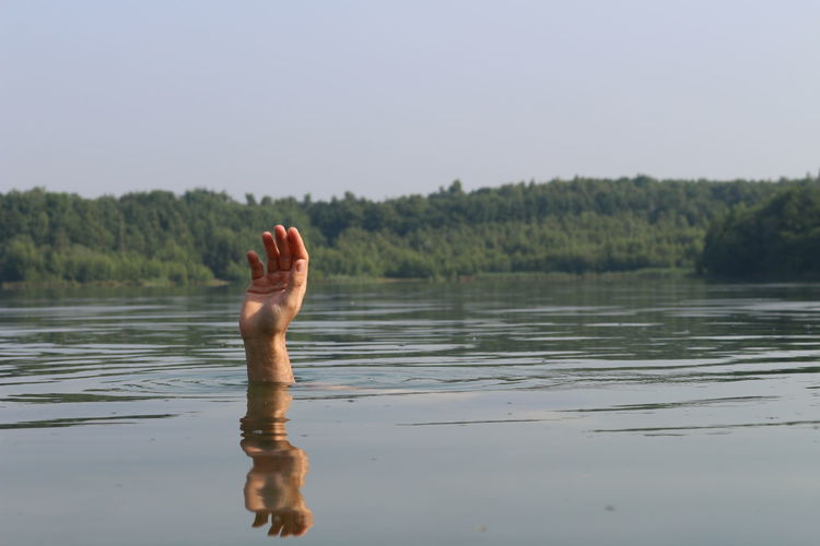 Cropped hand of person drowning in lake