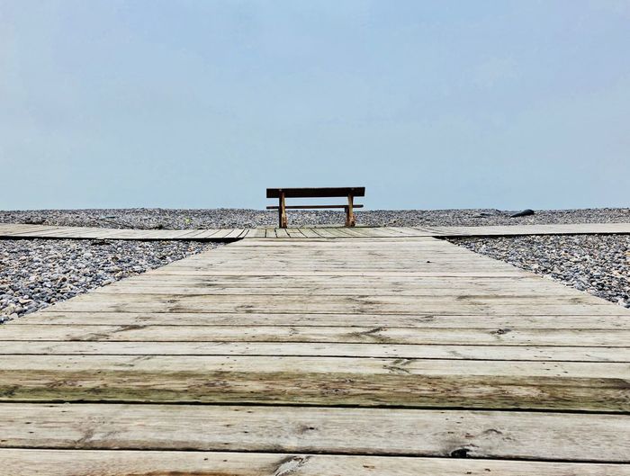 Empty wooden pier on beach against clear sky
