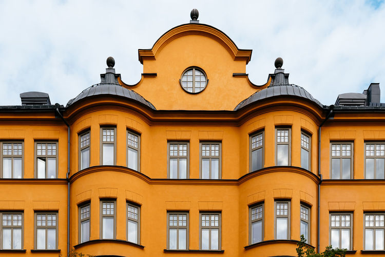 Traditional residential house in stockholm. yellow painted facade against sky.