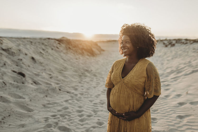 Portrait of pregnant mother in third trimester at beach at sunset