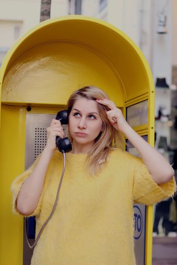 Young woman talking on telephone booth