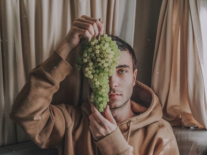 Portrait of young man holding grapes